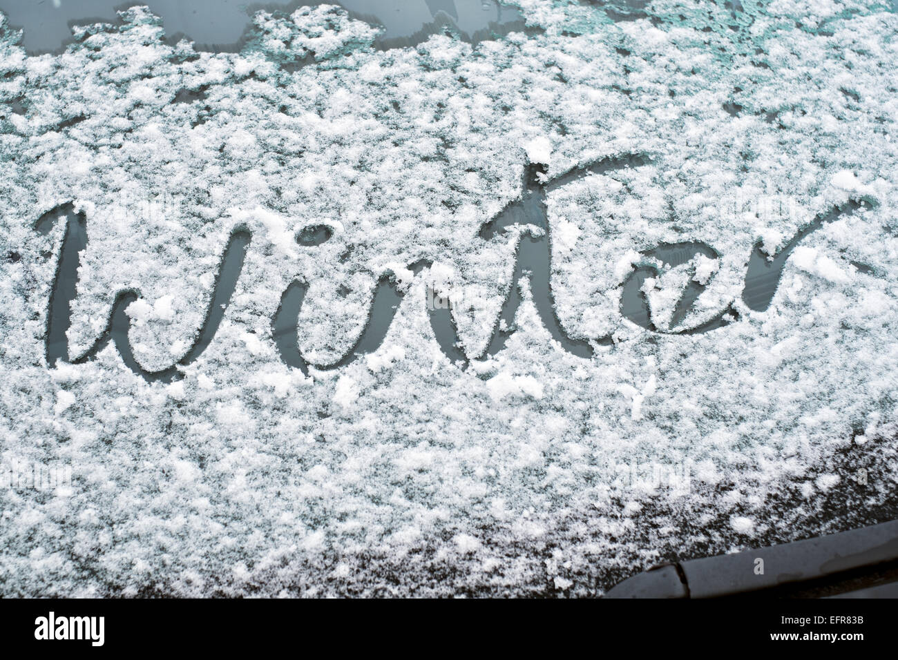 La parola inverno scritto su un fiocco di neve coperto parabrezza di vetro Foto Stock