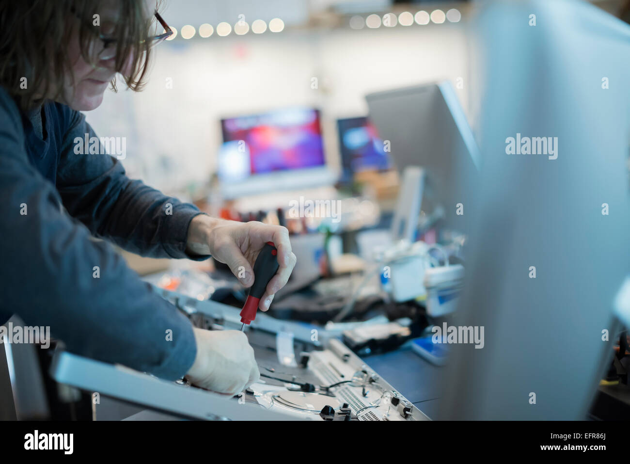 Una m un utilizzando un cacciavite su schede di circuito di un computer. Tecnico di riparazione. Foto Stock