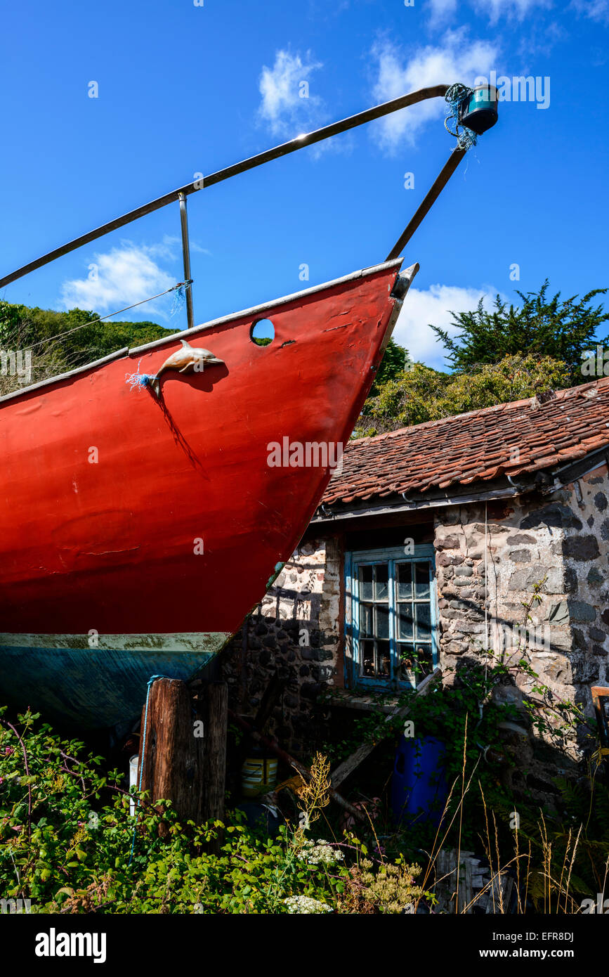 Old Red Boat in piedi alto e asciutto in un giardino cottage, Porlock, Somerset. Foto Stock