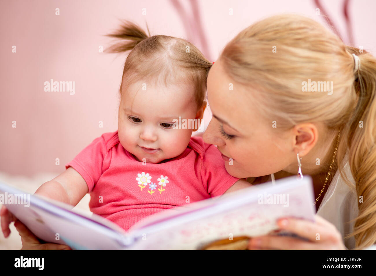 Madre felice di leggere un libro per bambina Foto Stock