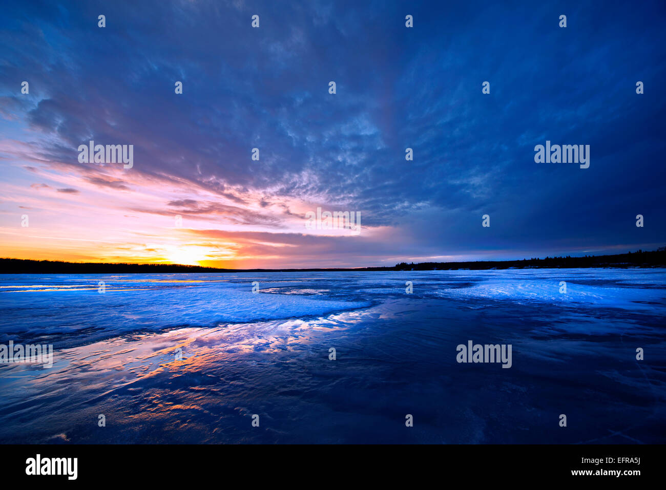 Un lago ghiacciato al tramonto e la vista del sole all'orizzonte. Foto Stock