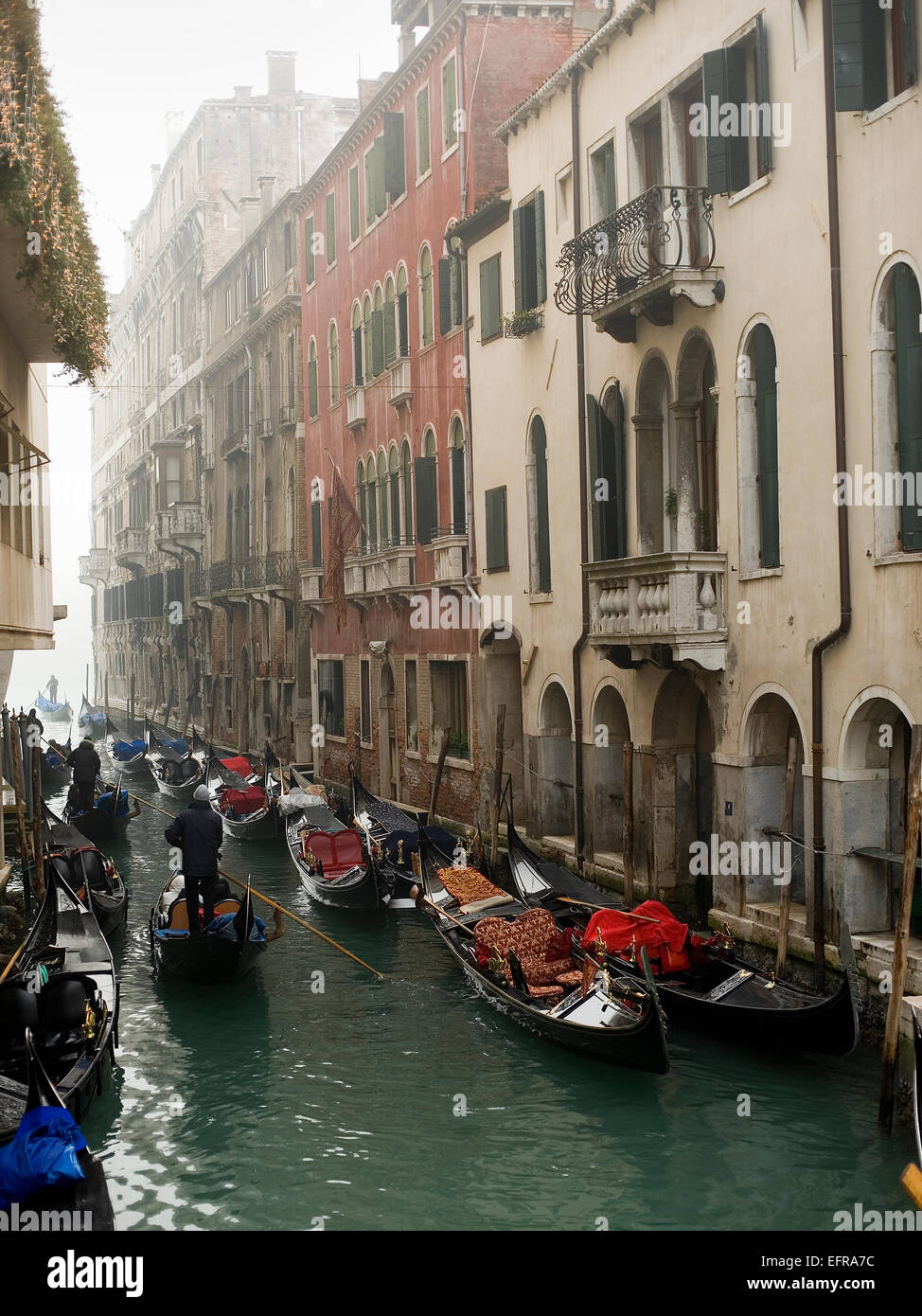Persone barche nebbia nebbia canal gondola gondoliere Venezia acqua case storiche balconi turismo sito UNESCO Foto Stock