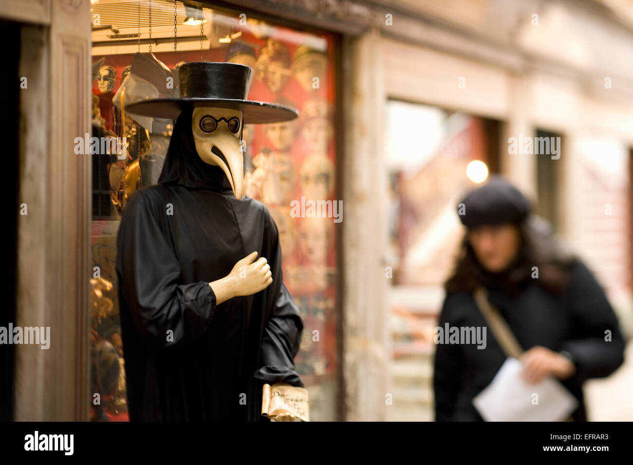Due persone in strada a Venezia, uno in un costume di carnevale con grande cappello e maschera di uccello Foto Stock