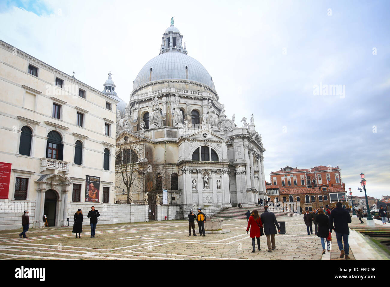 La gente camminare e visita della città di fronte alla chiesa di Santa Maria della Salute, dal canal Grande a Venezia, Italia. Foto Stock