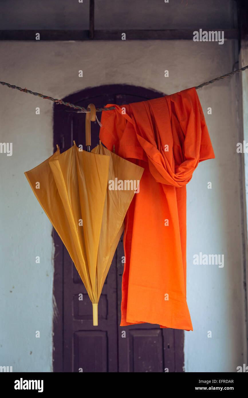 Tunica arancione e ombrello appeso, Luang Prabang, Laos. Foto Stock