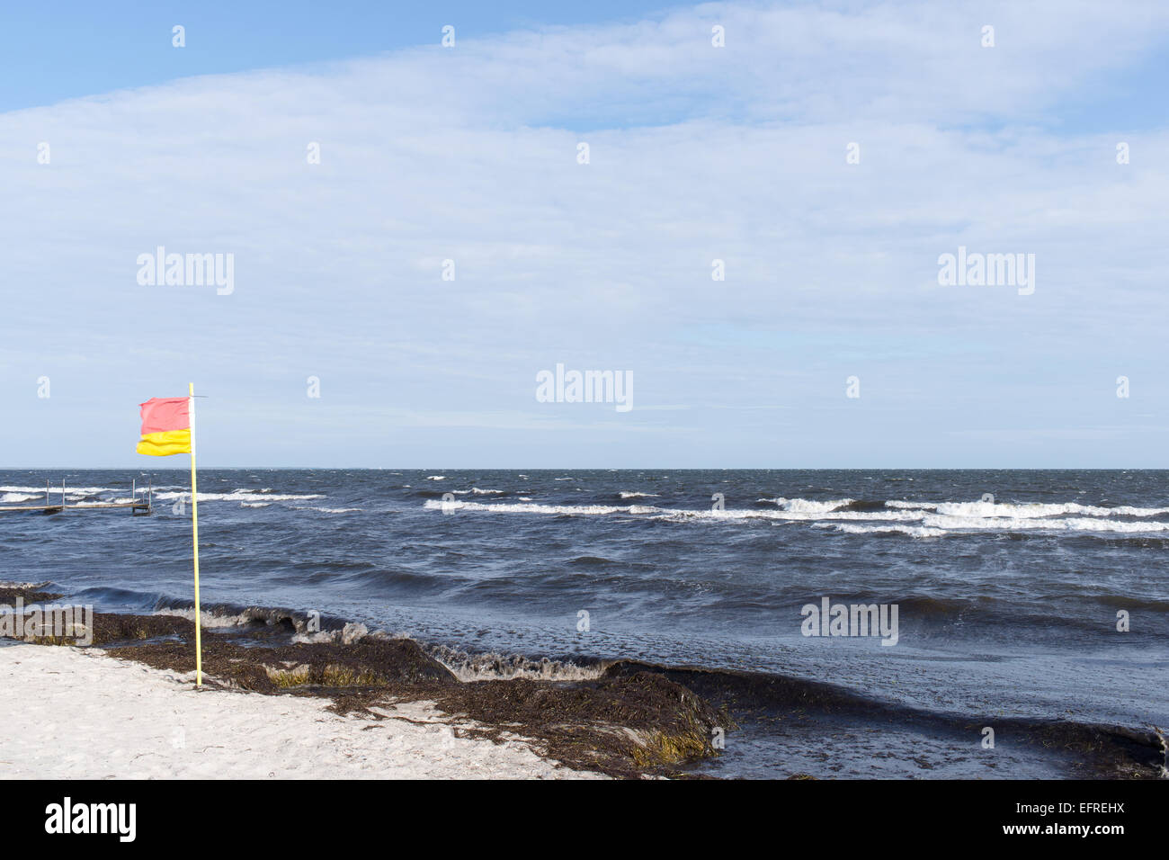 Rosso e giallo spiaggia bandiera turbinano nella brezza su una spiaggia in Danimarca Foto Stock