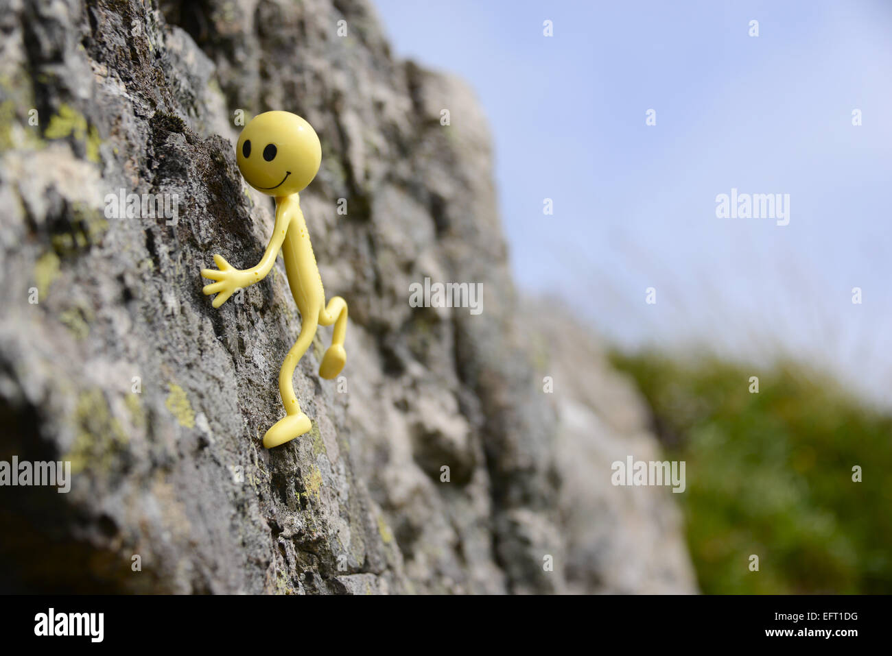 Gialli Smiley uomo in vacanza nelle Ebridi Esterne - egli qui di arrampicata di nuovo nel sole su Eriskay Foto Stock