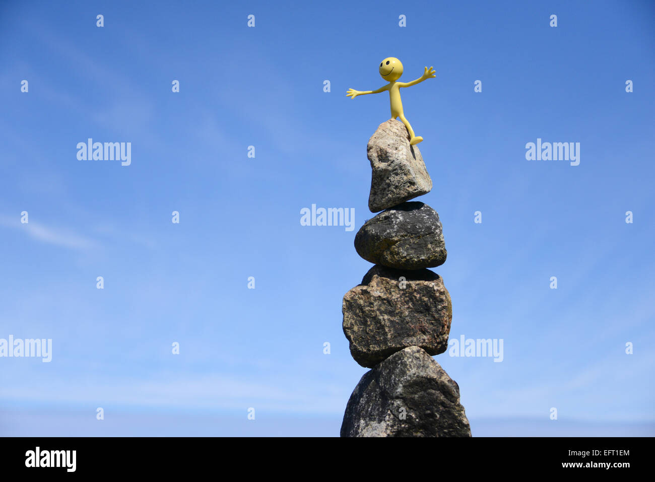 Gialli Smiley uomo in vacanza nelle Ebridi Esterne - qui è in cima a una roccia bilanciare nuovamente al di sotto di un luminoso cielo blu su Eriskay Foto Stock