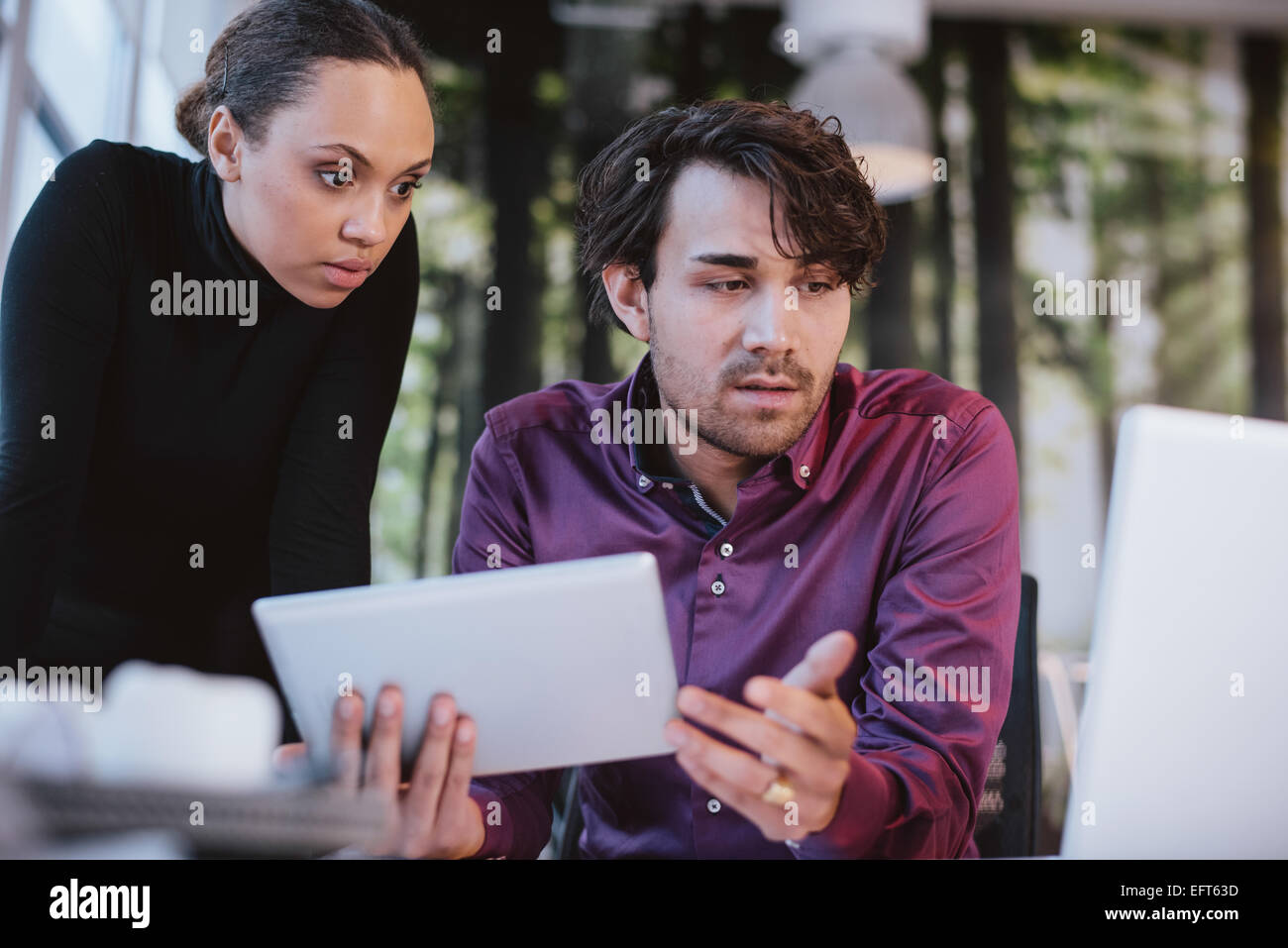 Due giovani professionisti che lavorano insieme su un progetto. I dirigenti di Creative con tavoletta digitale e portatile per la ricerca Foto Stock