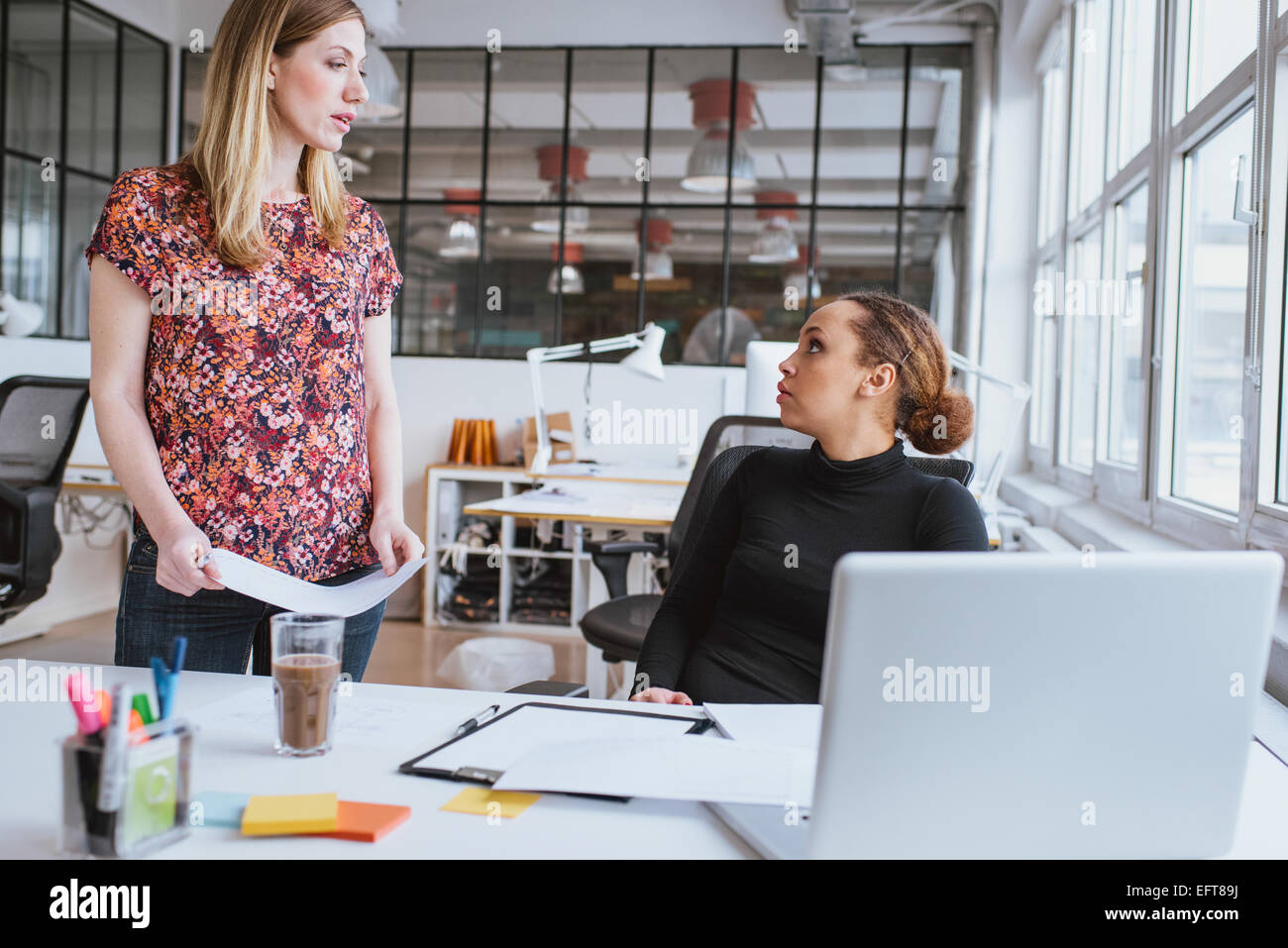 Giovane donna a discutere di lavorare con un collega. Due giovani imprenditrice presso l'ufficio. Foto Stock