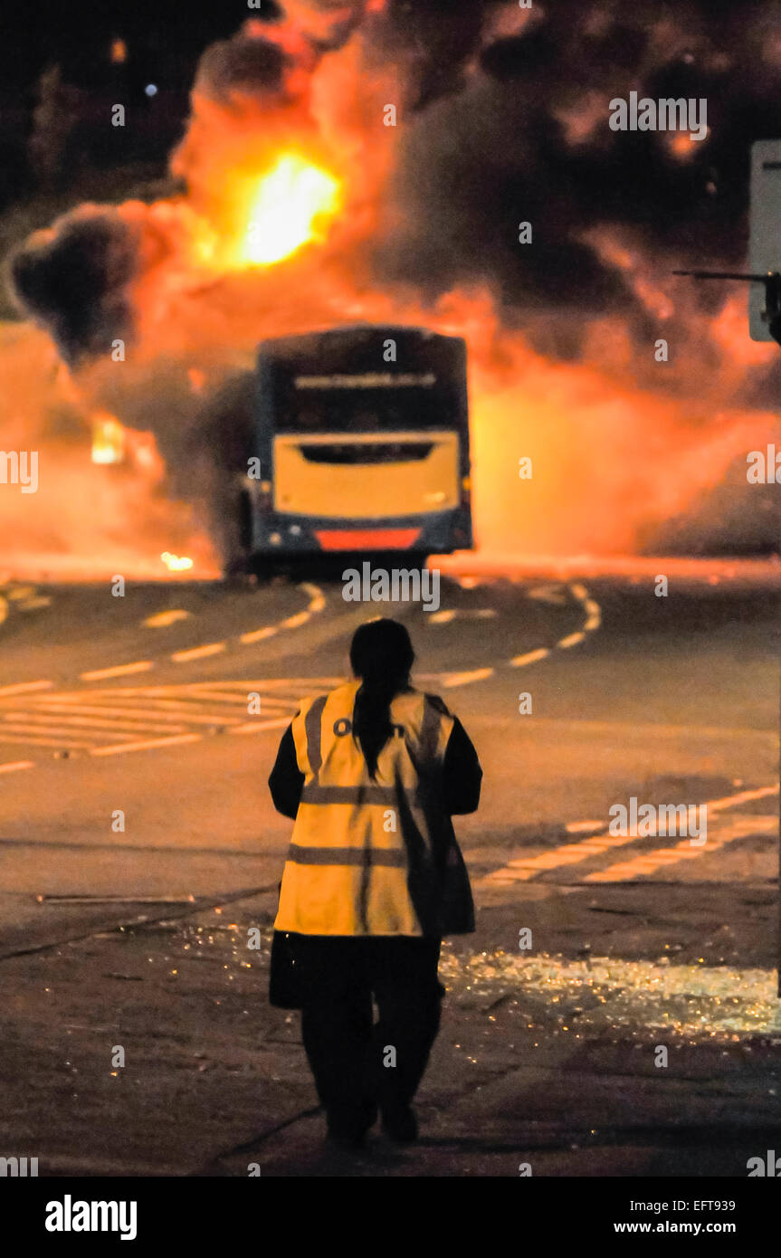 Un autista di autobus orologi come ella è costretto fuori la sua bus, e è impostato sul fuoco durante una sommossa. Foto Stock