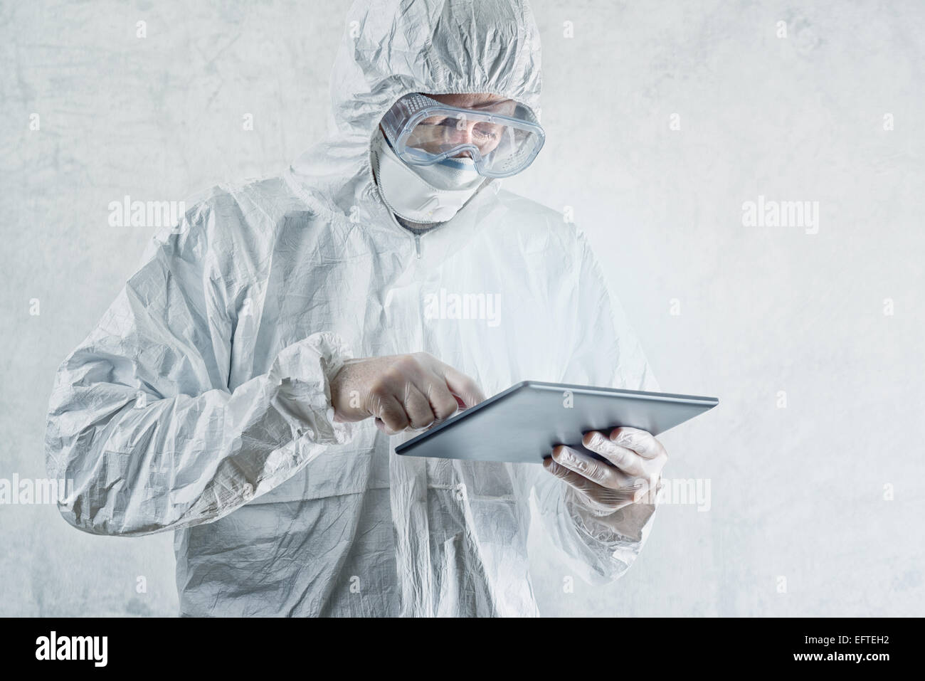 Scienziato di chimica in laboratorio protettivo Abbigliamento tramite Digital Computer tablet Foto Stock