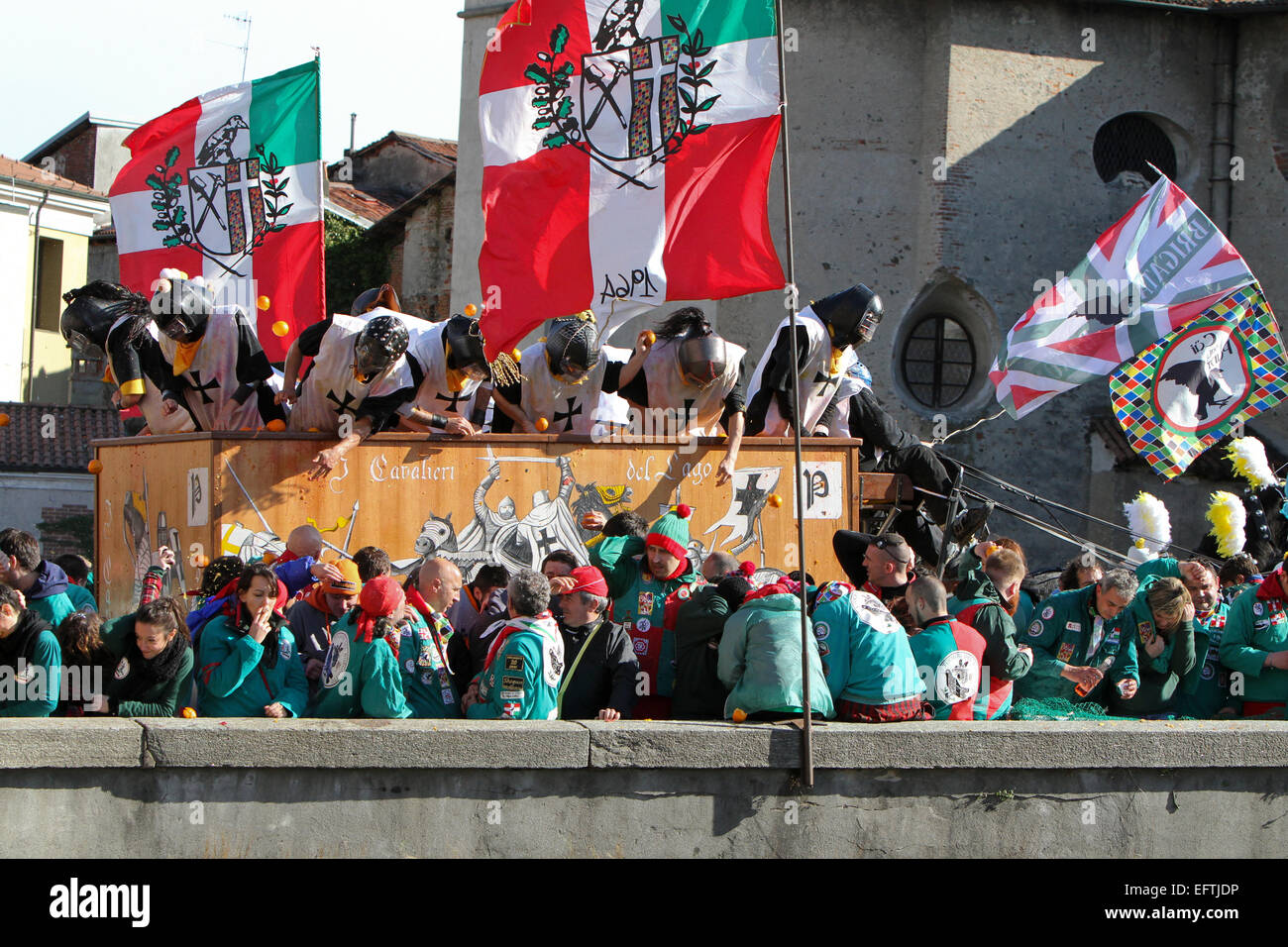 Un carrello attraversa lo stretto ponte sul fiume Dora come la lotta infuria durante "battaglia delle Arance" al Carnevale di Ivrea. Foto Stock