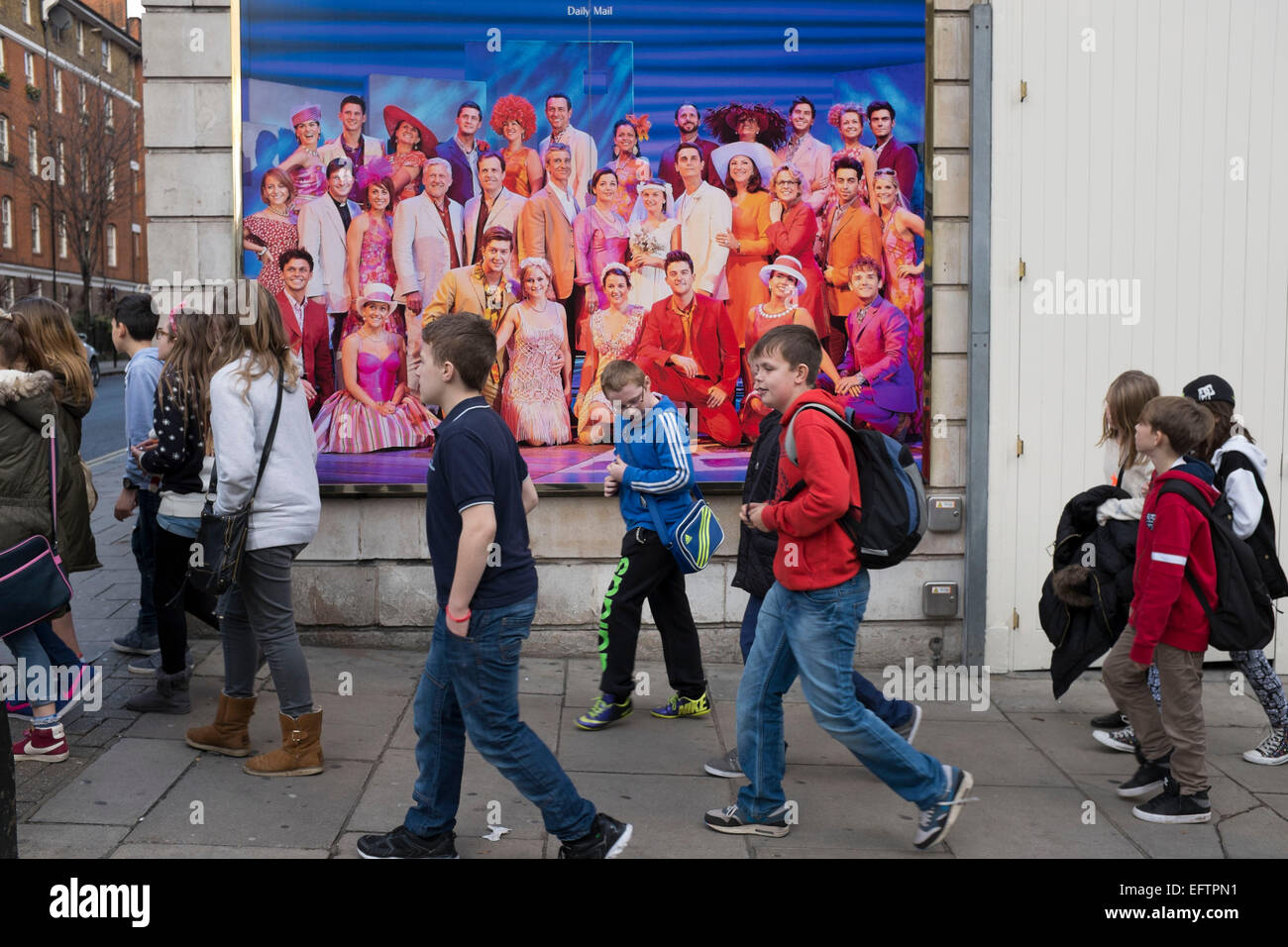 Gruppo di bambini a piedi passato un poster pubblicitari a West End Musical, Londra, Regno Unito. Foto Stock