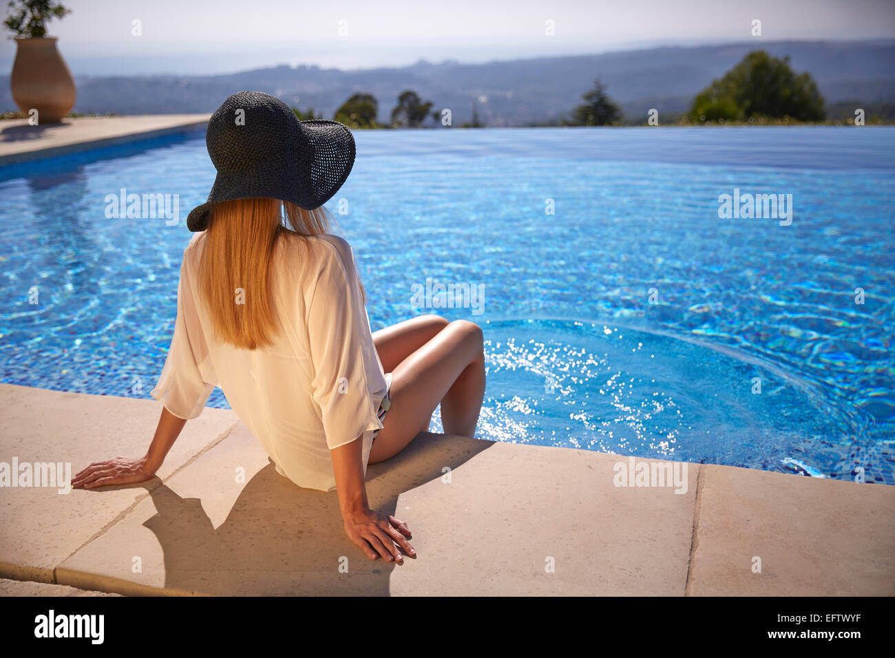 Giovane donna seduta presso la piscina in vacanza nel sud della Francia Foto Stock