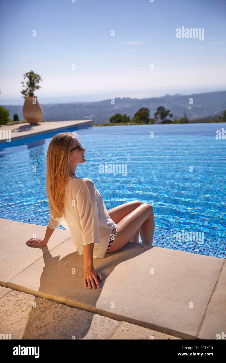 Giovane donna seduta presso la piscina in vacanza nel sud della Francia Foto Stock