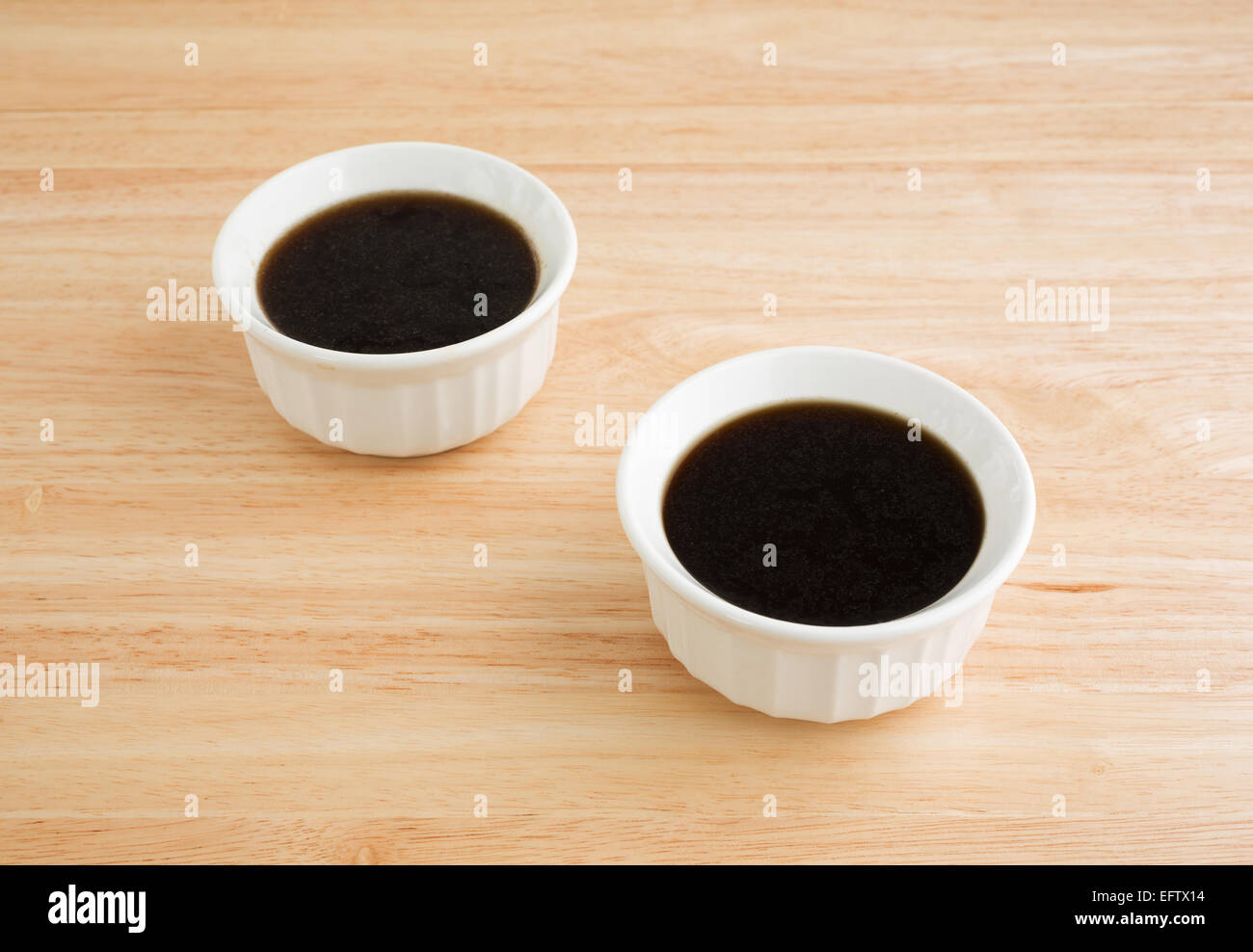 Due ciotole di Au Jus salsa su una tavola di legno alto. Foto Stock