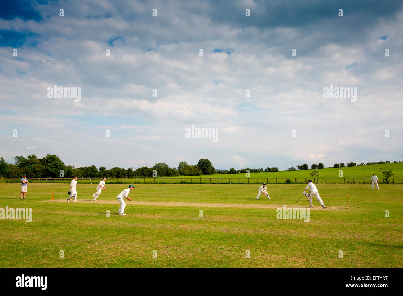 Scena rurale con vista giocatori di cricket Gioca partita di cricket sul campo di cricket Foto Stock