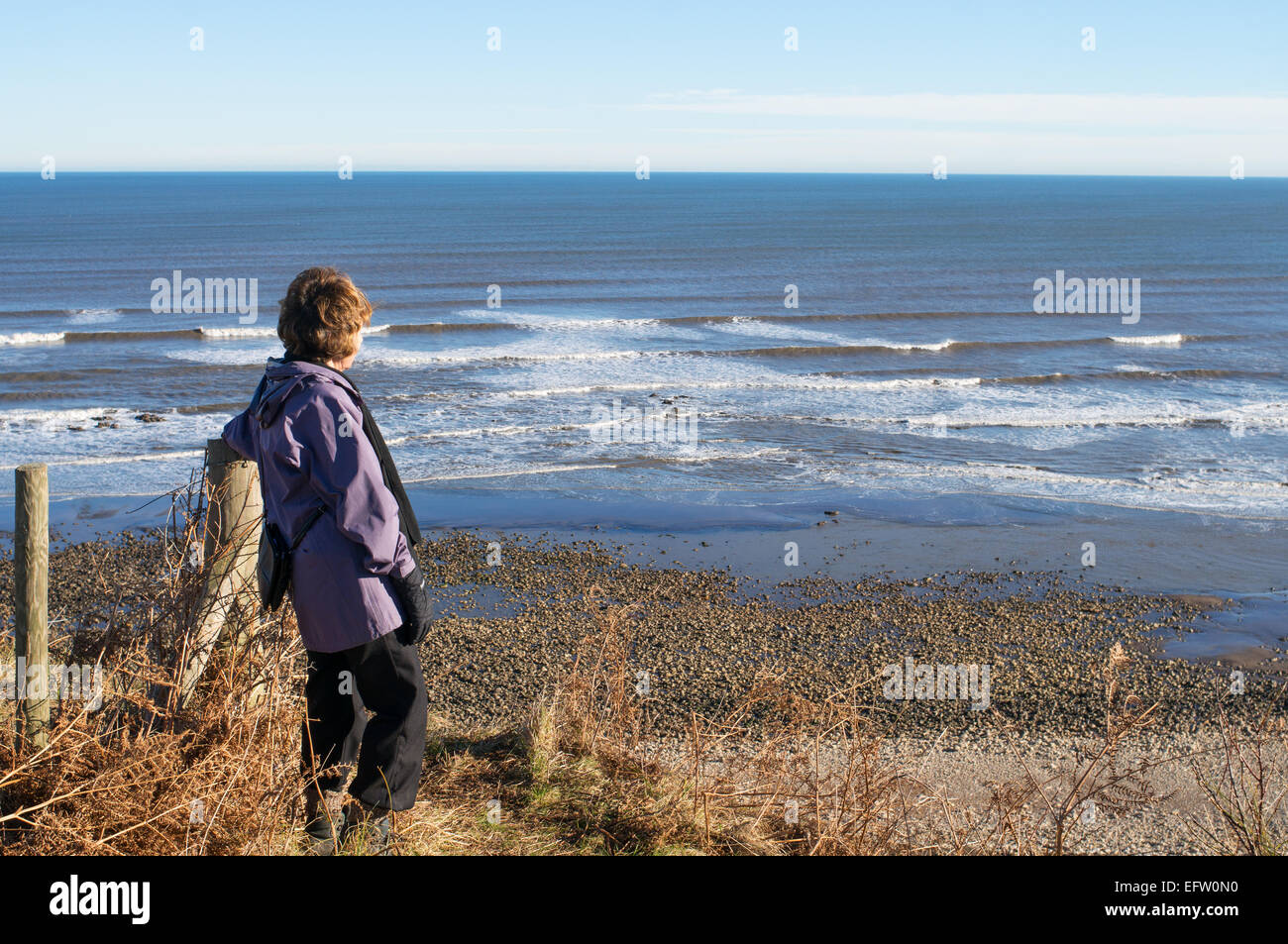 Donna che guarda al Mare del Nord, vicino Easington, Durham coast visto dall'Inghilterra Coast Path, REGNO UNITO Foto Stock
