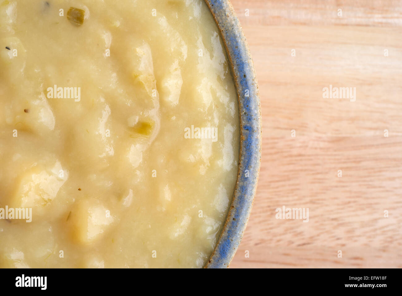 Top vista ravvicinata di un serving della fecola di patate e zuppa di porri in una ciotola su una tavola di legno alto. Foto Stock