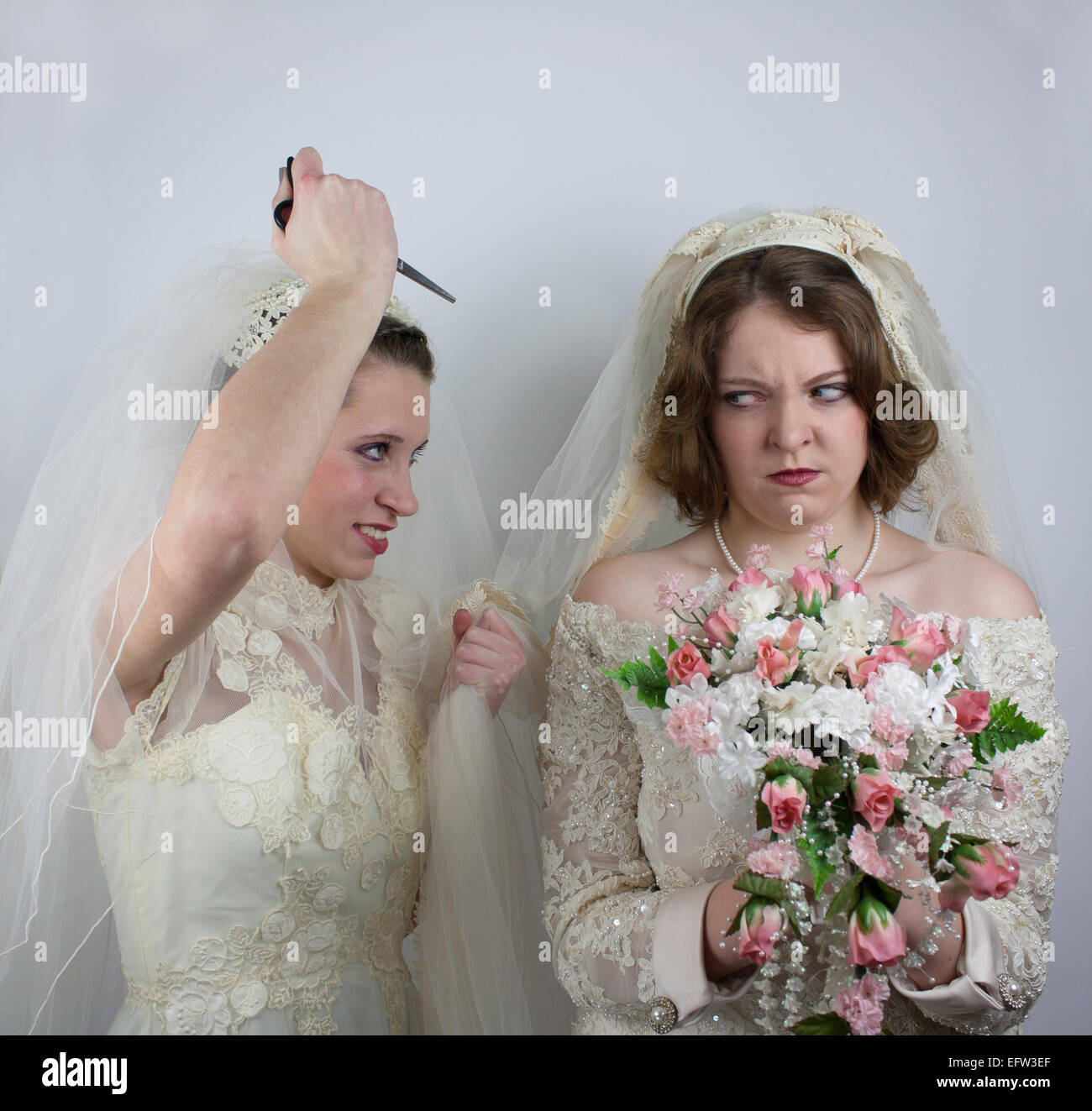 Una sposa ha il suo braccio sollevato con una forbice di circa di strappare  l'altra sposa velo Foto stock - Alamy
