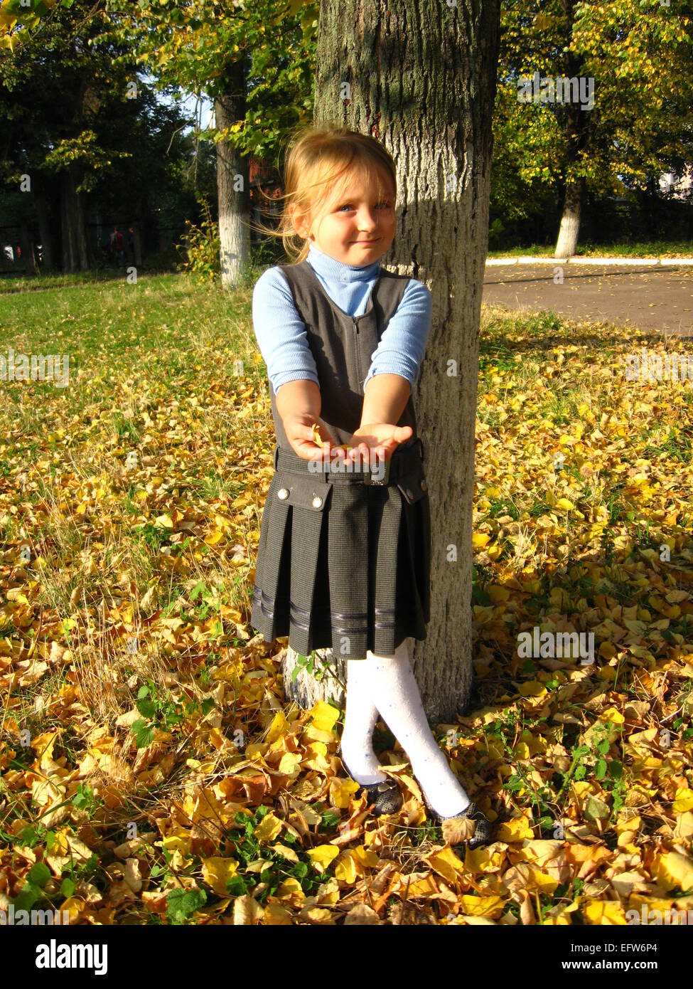 Bambina con foglie di colore giallo nel parco in autunno Foto Stock