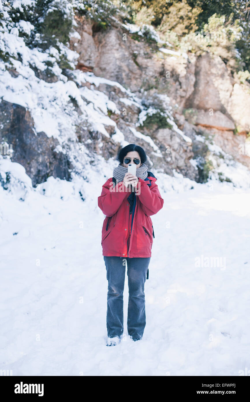 Donna su una montagna innevata di scattare una foto con il suo cellulare Foto Stock