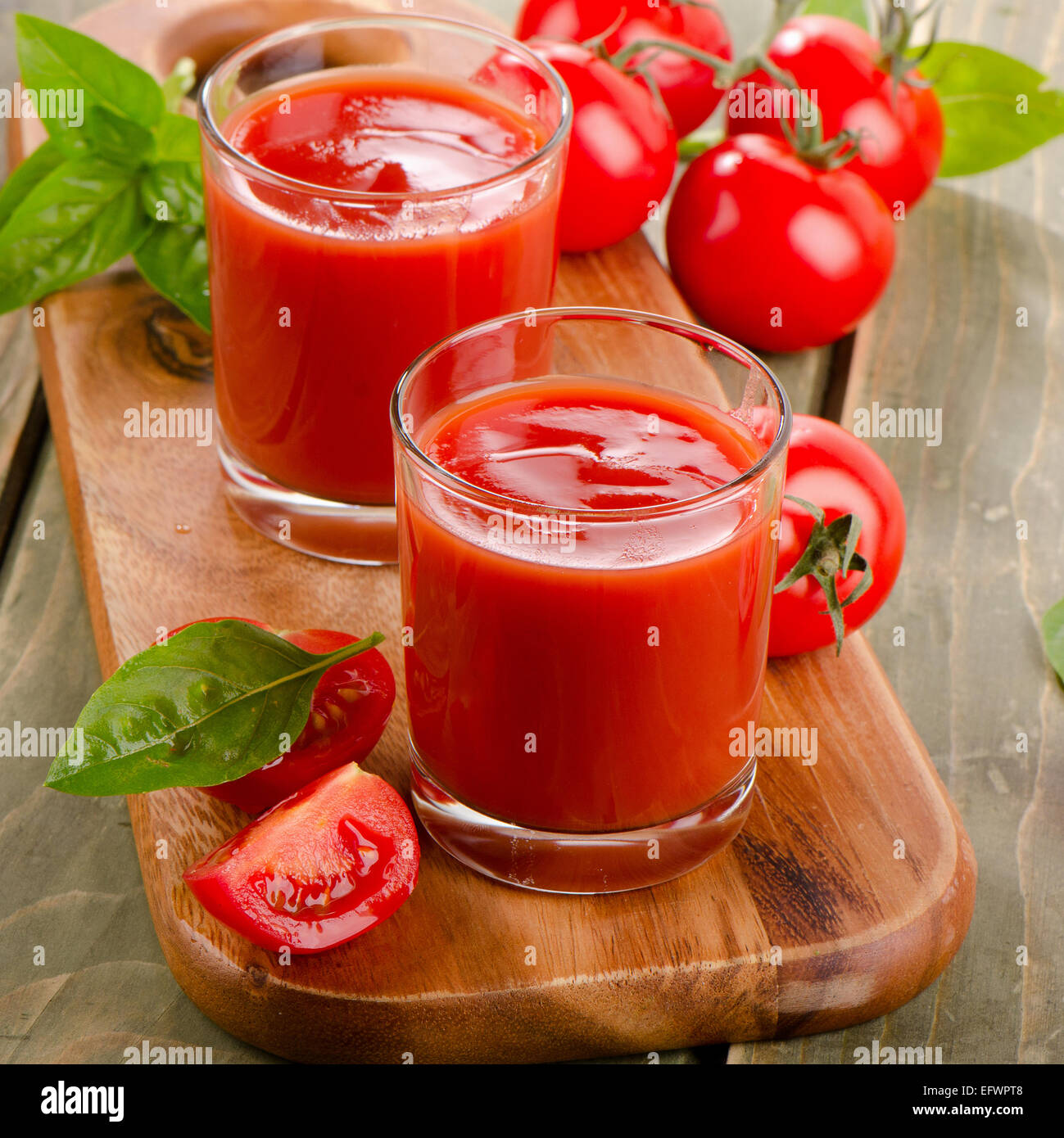 I succhi di pomodoro e i pomodori maturi su sfondo di legno. Messa a fuoco selettiva Foto Stock