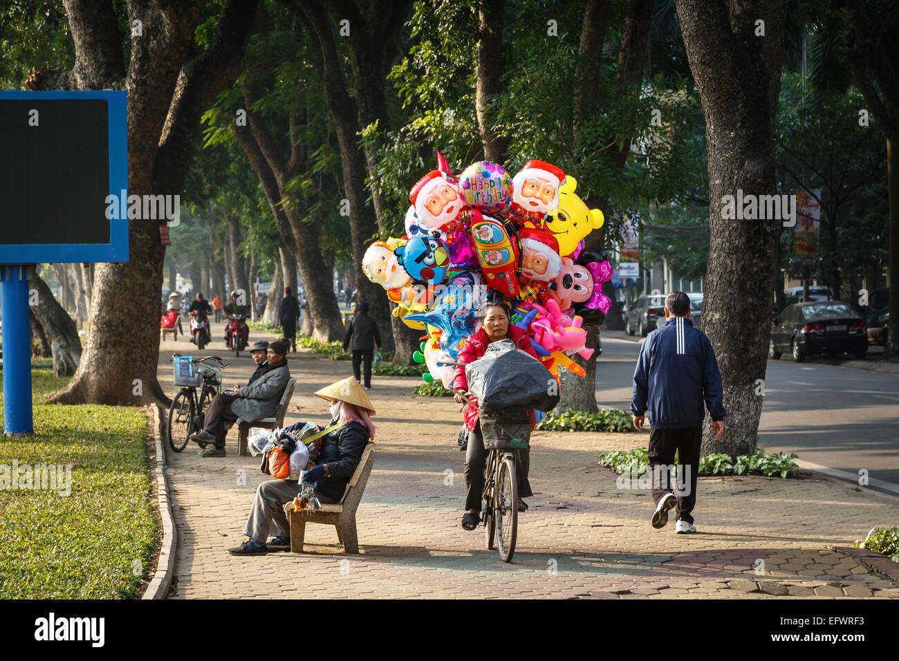 Donna vendita di palloncini fuori la sua bicicletta, Hanoi, Vietnam. Foto Stock