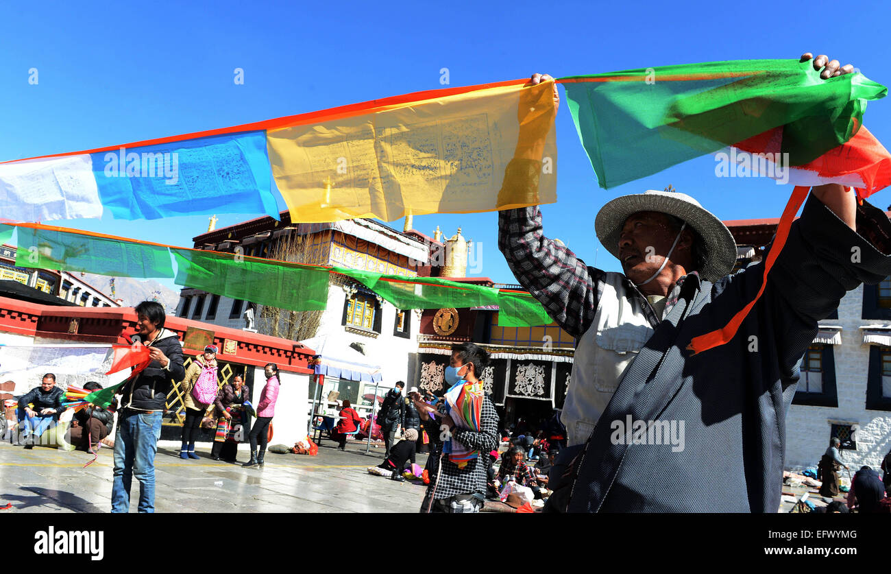 Lhasa, la Cina della regione autonoma del Tibet. Xi Febbraio, 2015. I devoti appendere bandiere di preghiera ad un palo vicino il tempio del Jokhang a Lhasa, capitale del sud-ovest della Cina di regione autonoma del Tibet, 11 febbraio, 2015. Come il periodo del nuovo anno tibetano si avvicina, bandiere di preghiera legata a cinque poli che circonda il tempio del Jokhang sono state sostituite da quelle nuove in conformità con la tradizione tibetana. Il nuovo anno sotto il calendario tibetano coincide con il Festival di primavera di quest'anno, che cade nel febbraio 19. Credito: Chogo/Xinhua/Alamy Live News Foto Stock