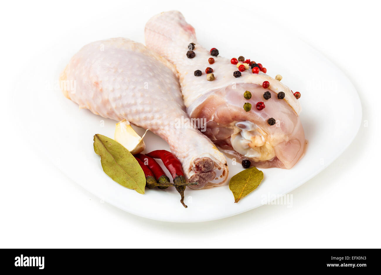 Il pollo crudo i piedi sulla piastra con spezie, sfondo bianco Foto Stock