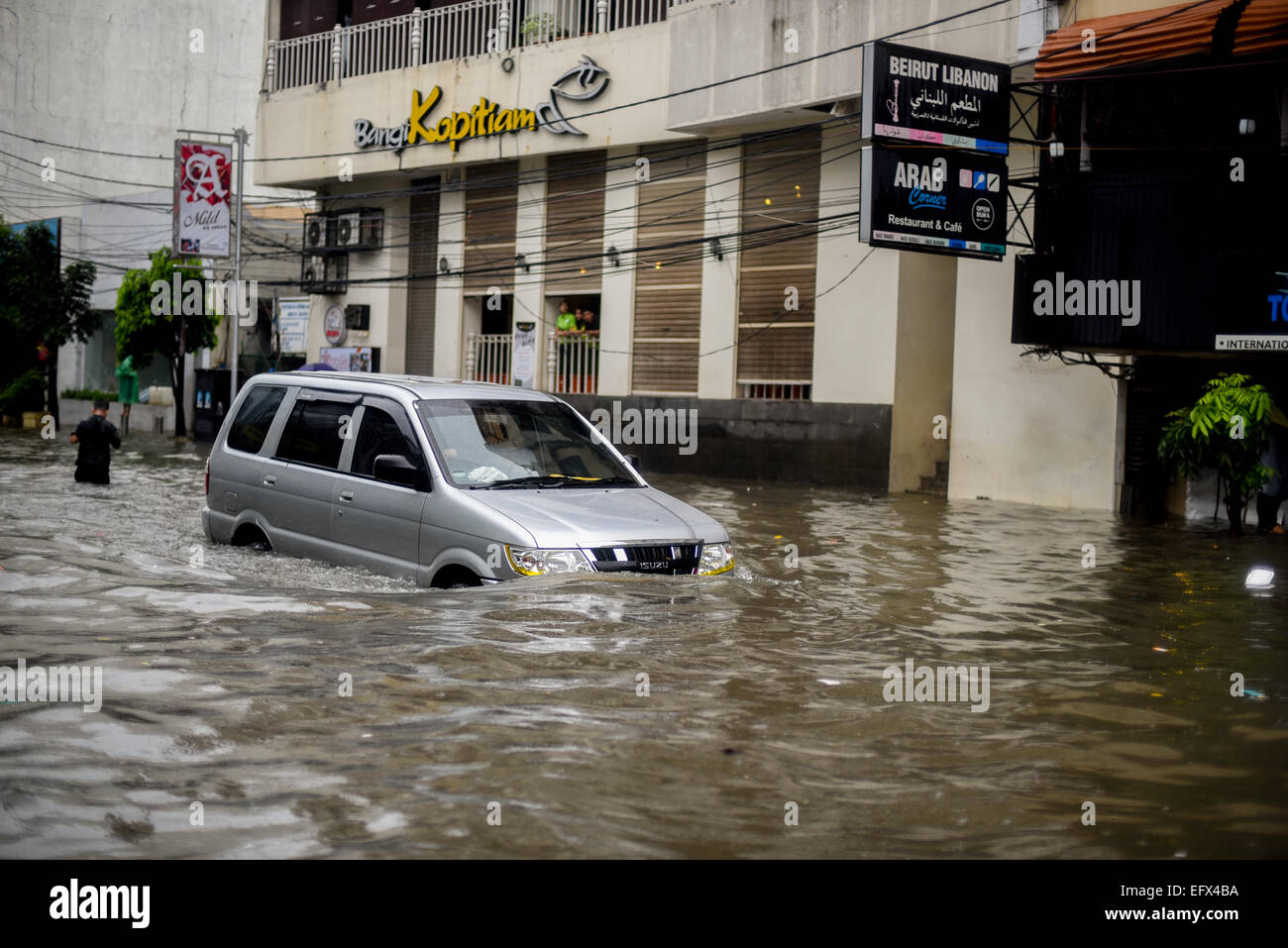 Un'auto che si muove attraverso l'acqua sommersa, dopo una pioggia continua ha lasciato l'area del centro di Jakarta allagato. Foto Stock