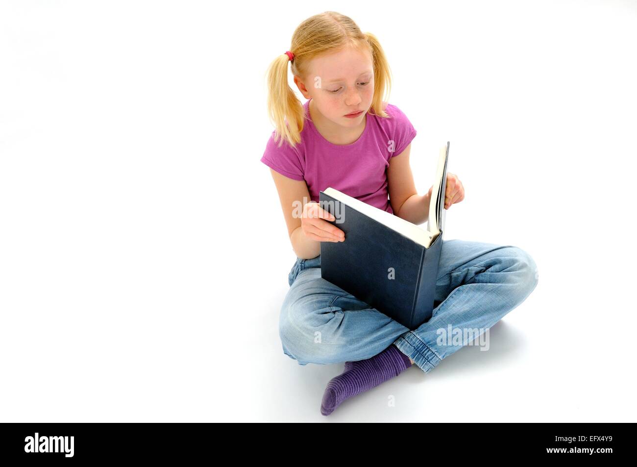 Pre-teen ragazza la lettura di un libro di grandi dimensioni Foto Stock