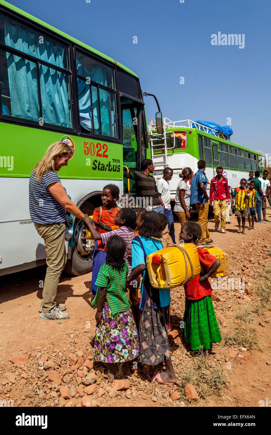 Una chat turistica europea ai bambini locali curiosi mentre aspettano il suo autobus rotto per essere fisso, Kono, Etiopia Foto Stock