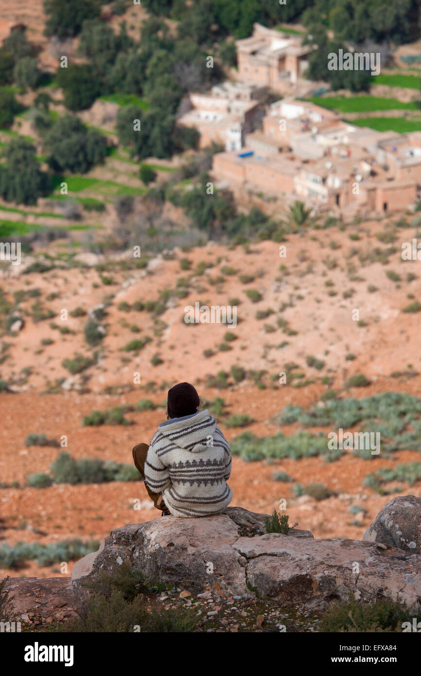 Vista posteriore dell'uomo seduto sulle rocce sopra la valle, Atlante, Marocco Foto Stock