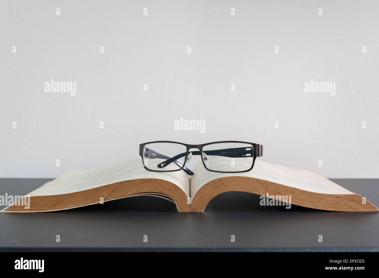 Libro aperto e degli occhiali sulla scrivania Foto Stock