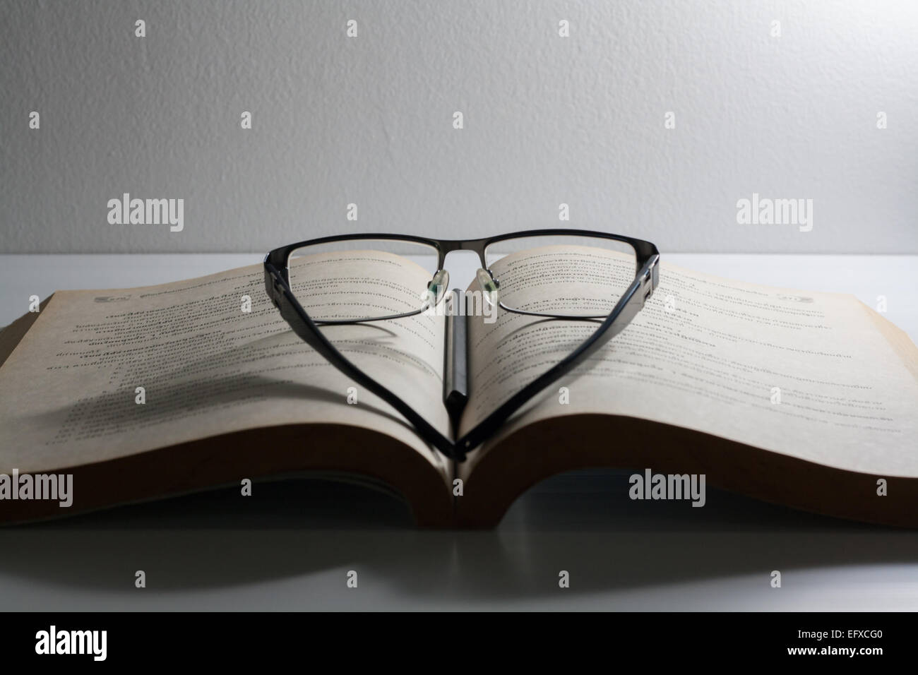 Libro aperto e degli occhiali sulla scrivania Foto Stock