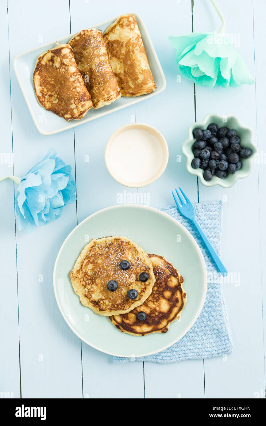 Pancake con mirtilli e latte su sfondo blu Foto Stock