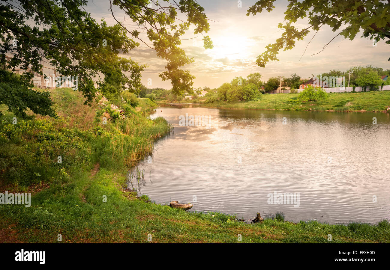 Bel Tramonto sul lago vicino a un villaggio Foto Stock