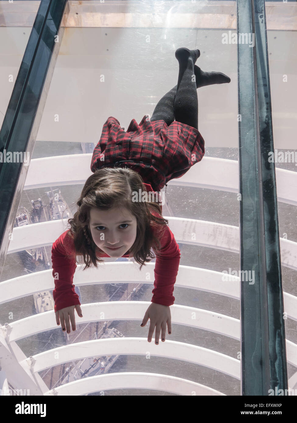 Una giovane ragazza distesa sul pavimento di vetro della Spinnaker Tower di Portsmouth, Inghilterra Foto Stock