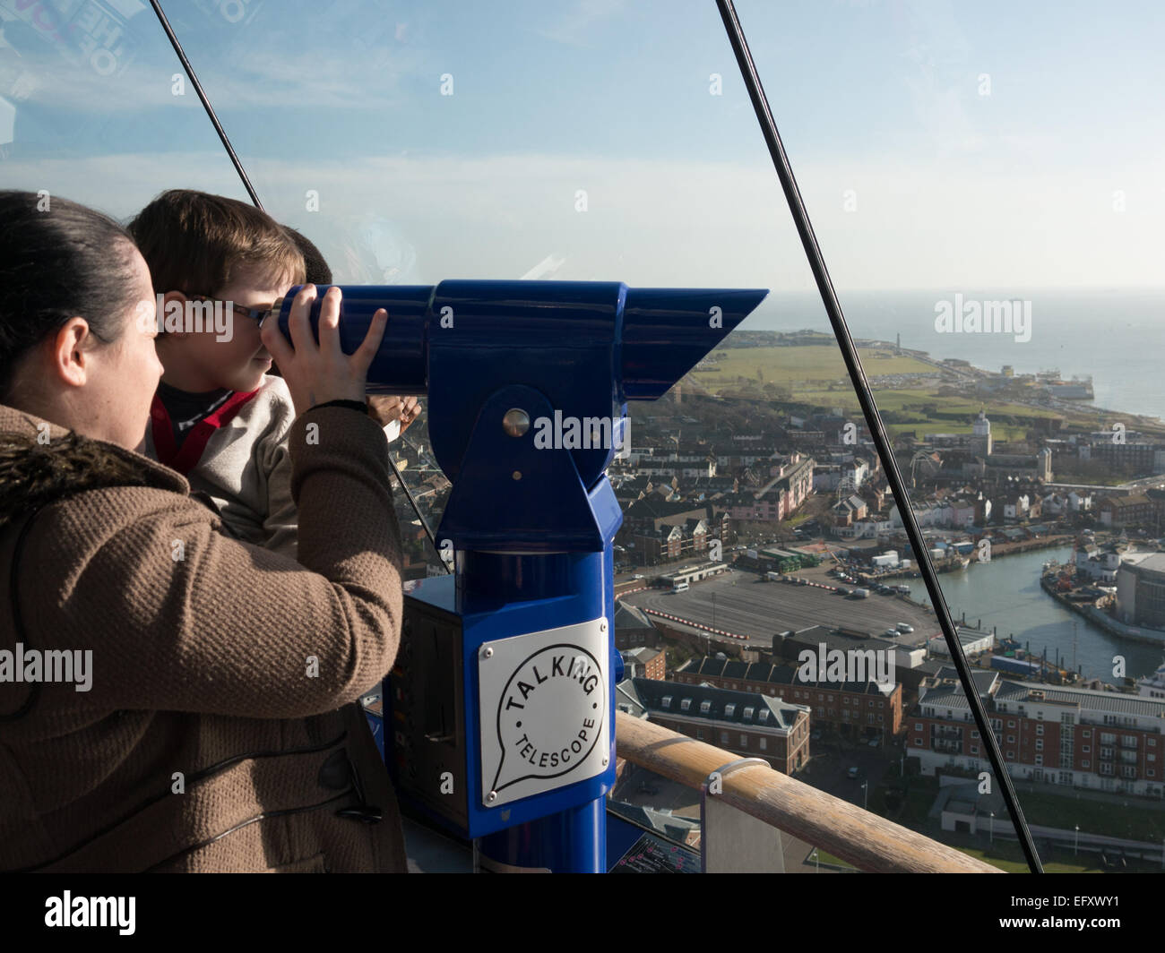 Una madre e un bambino guardare attraverso un telescopio parlante sul deck di visualizzazione numero uno della Spinnaker Tower, Portsmouth, Inghilterra Foto Stock