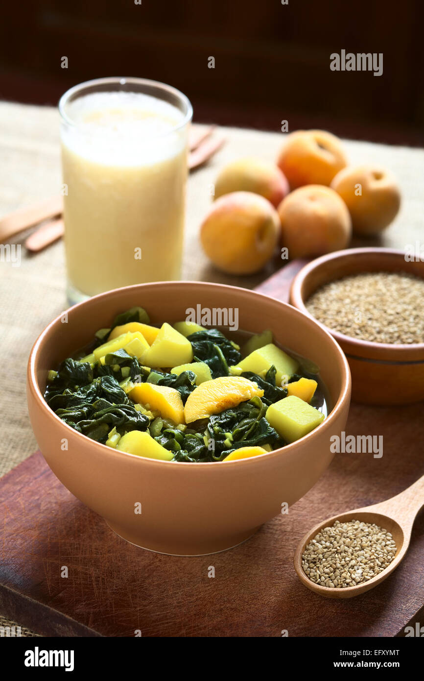 Ciotola di spinaci, di pesche e di patate piatto di curry con semi di sesamo, pesche e lassi nel retro fotografati con luce naturale Foto Stock