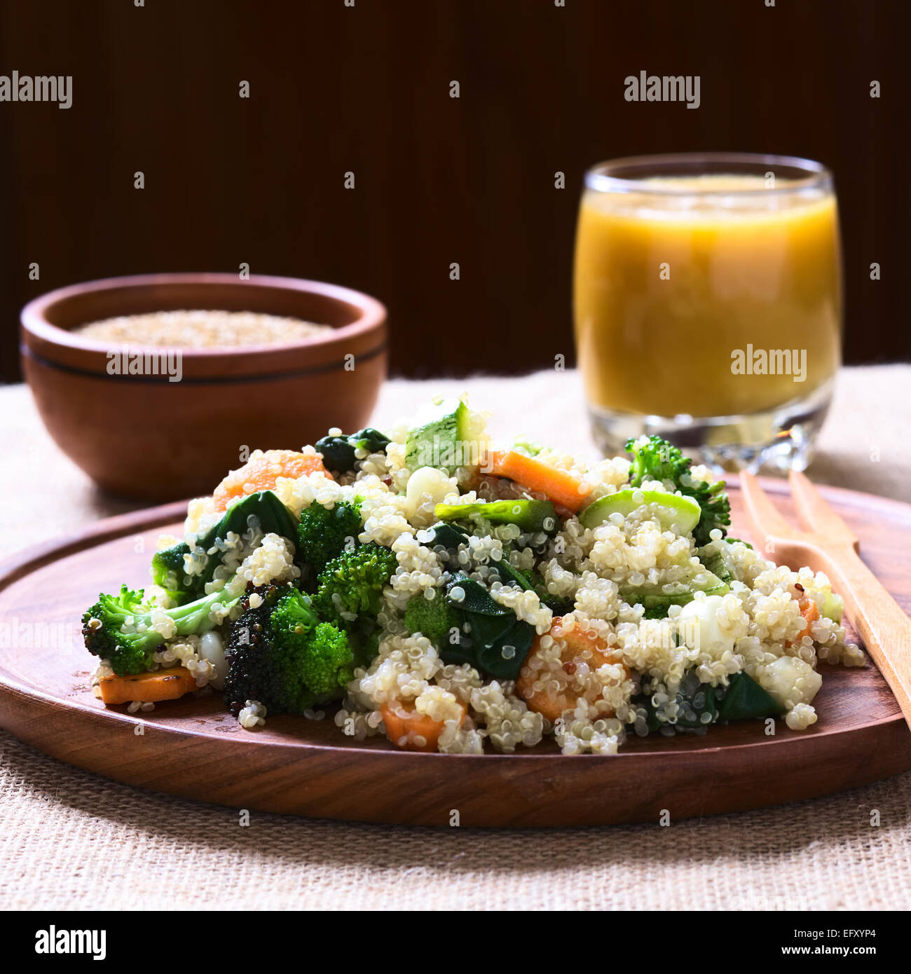 Cotto bianco semi di quinoa con verdure fritte (carota, broccoli, spinaci, zucchine, mais) sul piatto di legno Foto Stock