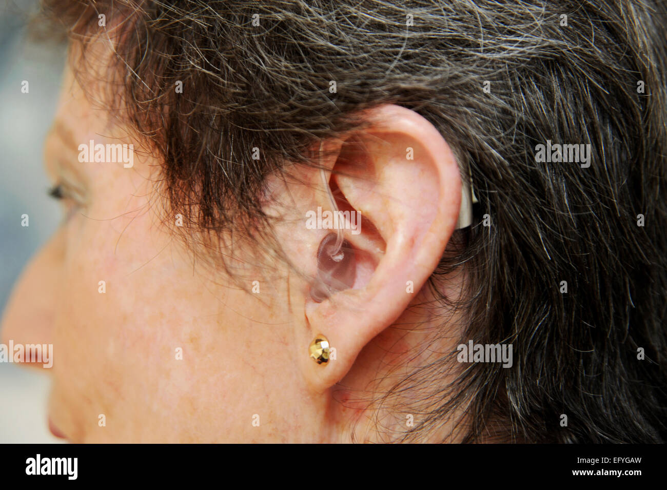 Signora anziana donna indossa femmina Hearing Aid nel suo orecchio con problemi di udito Foto Stock