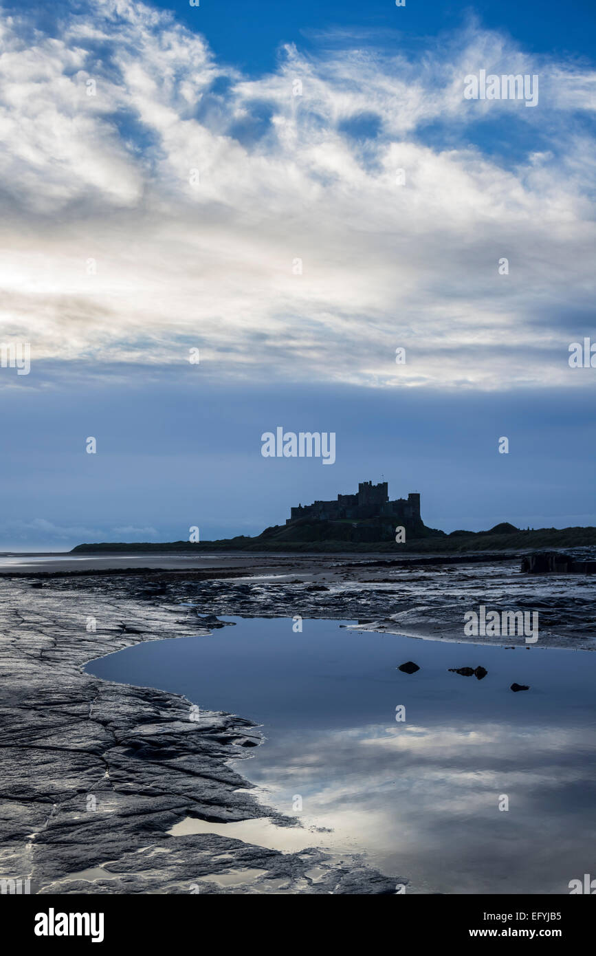 Il castello di Bamburgh alla prima luce da una pedana Whin ripiano di roccia a nord del castello, Northumberland, Inghilterra Foto Stock