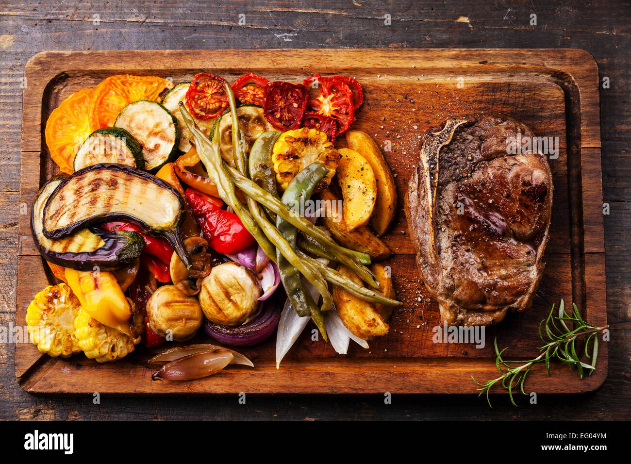 Club bistecca di manzo e verdure grigliate sul tagliere in legno scuro dello sfondo Foto Stock