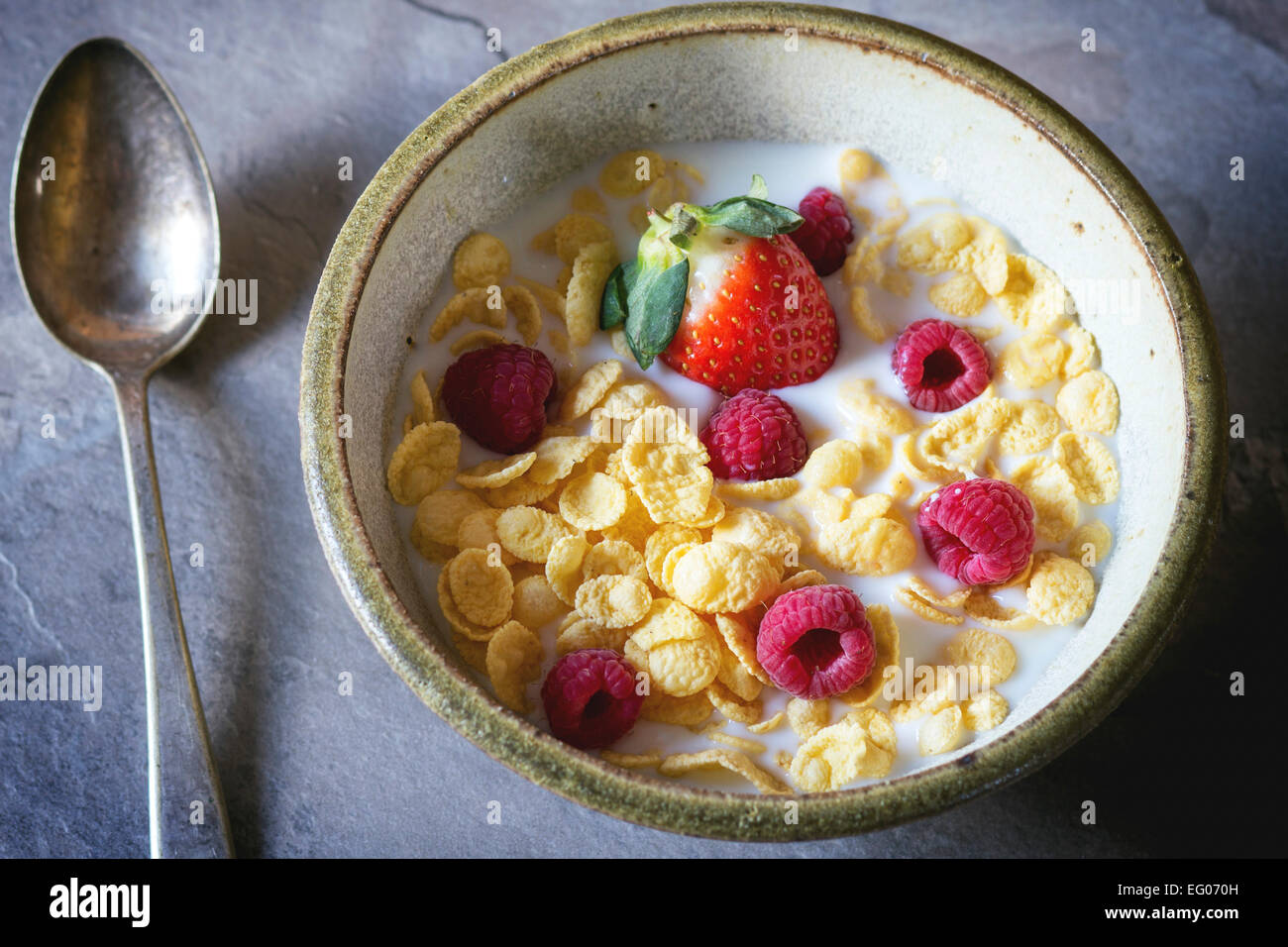 Cornflakes con latte e frutti di bosco in vaso di ceramica nella luce del giorno Foto Stock