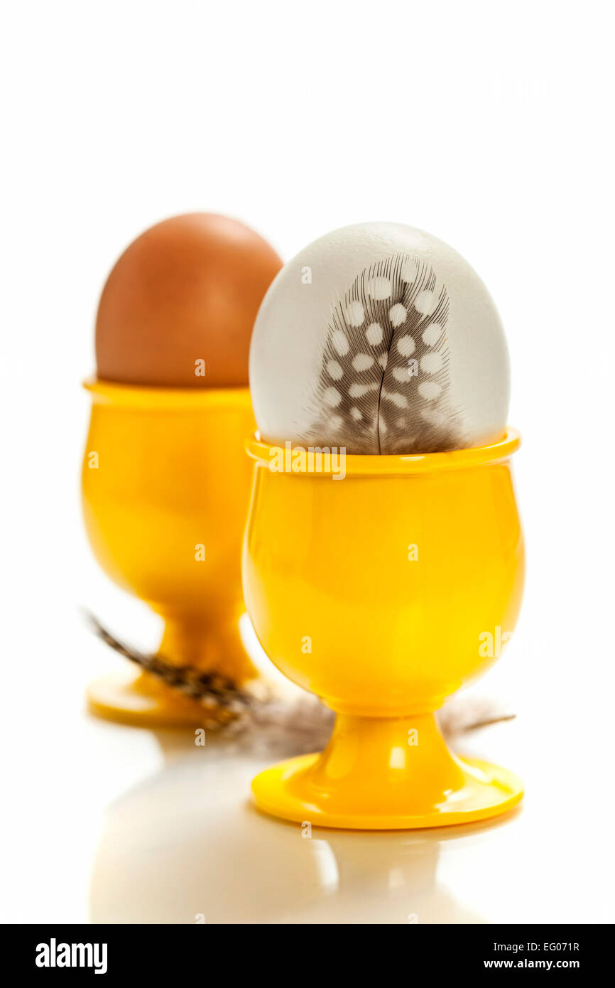 Uova in giallo eggcups isolato su bianco Foto Stock