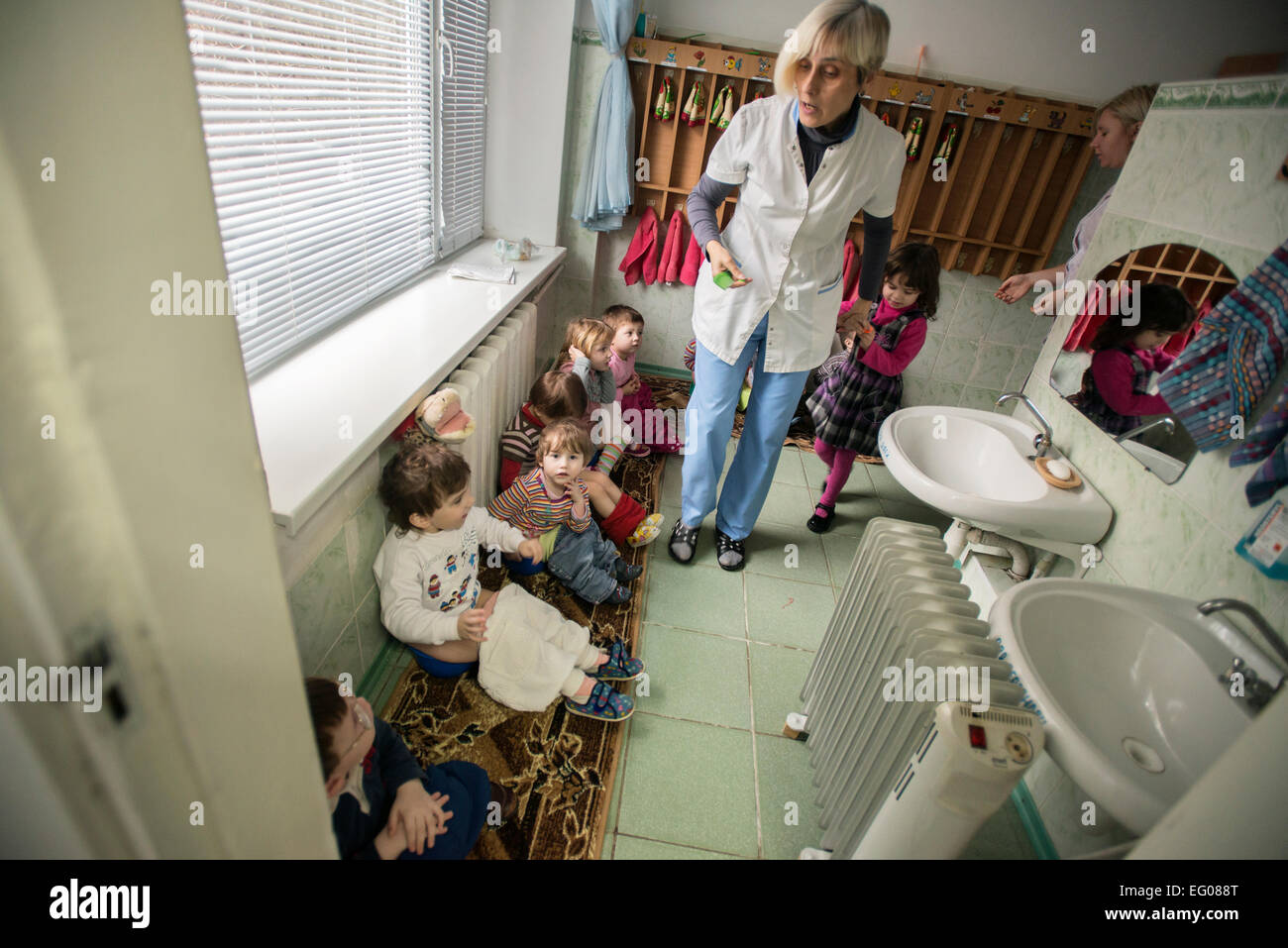 I bambini seduti su pentole in WC, orfanotrofio "Zhytomyr regionali di bambini a casa', Ucraina. 2 febbraio 2015. "Zhytomyr regionali di casa dei bambini' ha 67 bambini orfani da neonati a 4 anni di età. 25% di loro hanno mentale, disabilità intellettuale, HIV. Orfanotrofio ha più di 90% di adozione. Sin dal 2008 anno Ucraina fornendo programma di smantellamento orfanotrofio governativa, incluso il "Zhytomyr regionali di casa dei bambini". Foto di Oleksandr Rupeta Foto Stock