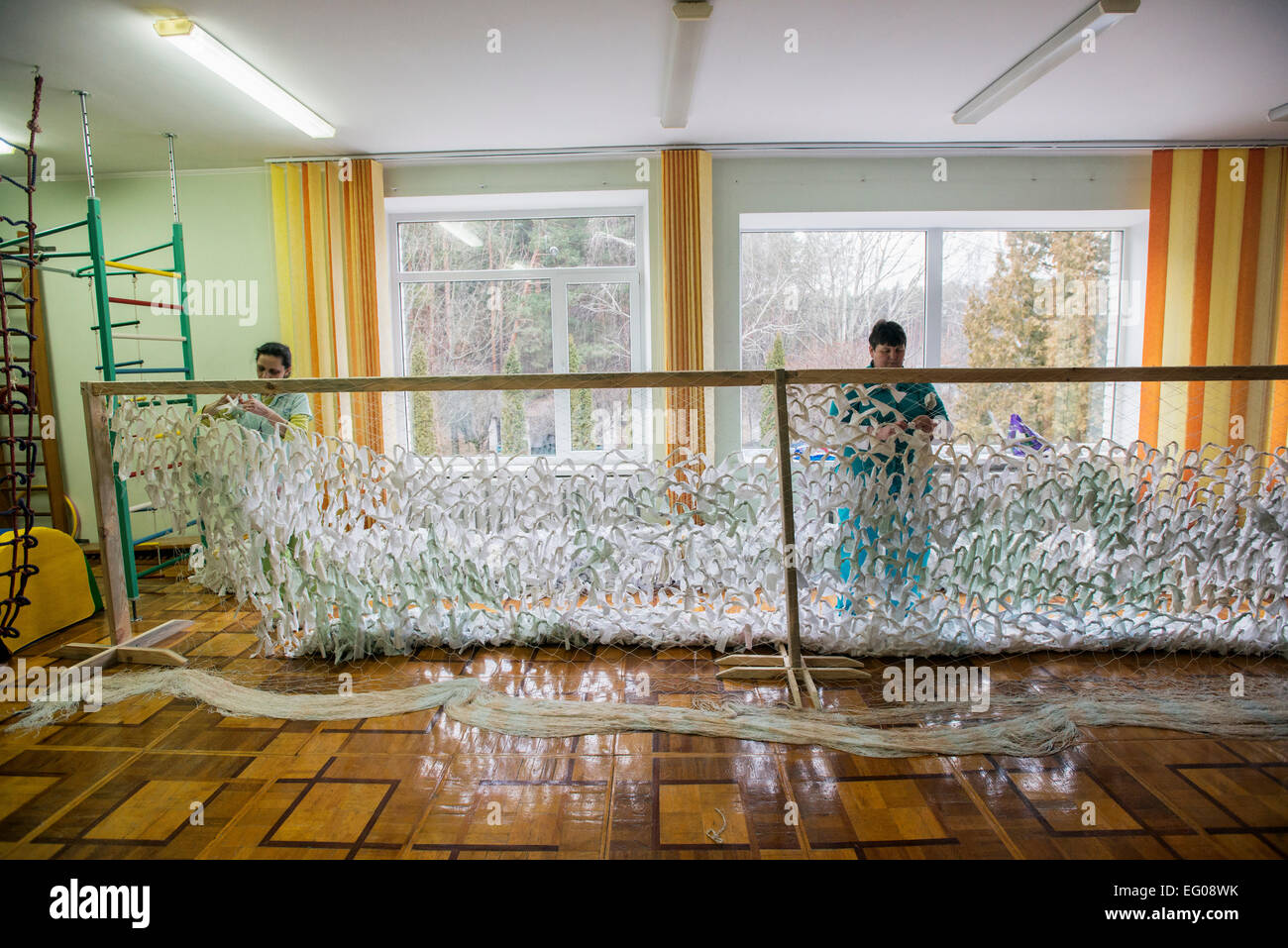 I lavoratori di un orfanotrofio a maglia il camuffamento di netto per i soldati combattono in ATO, orfanotrofio "Zhytomyr regionali di bambini a casa', Ucraina. 2 febbraio 2015. "Zhytomyr regionali di casa dei bambini' ha 67 bambini orfani da neonati a 4 anni di età. 25% di loro hanno mentale, disabilità intellettuale, HIV. Orfanotrofio ha più di 90% di adozione. Sin dal 2008 anno Ucraina fornendo programma di smantellamento orfanotrofio governativa, incluso il "Zhytomyr regionali di casa dei bambini". Foto di Oleksandr Rupeta Foto Stock